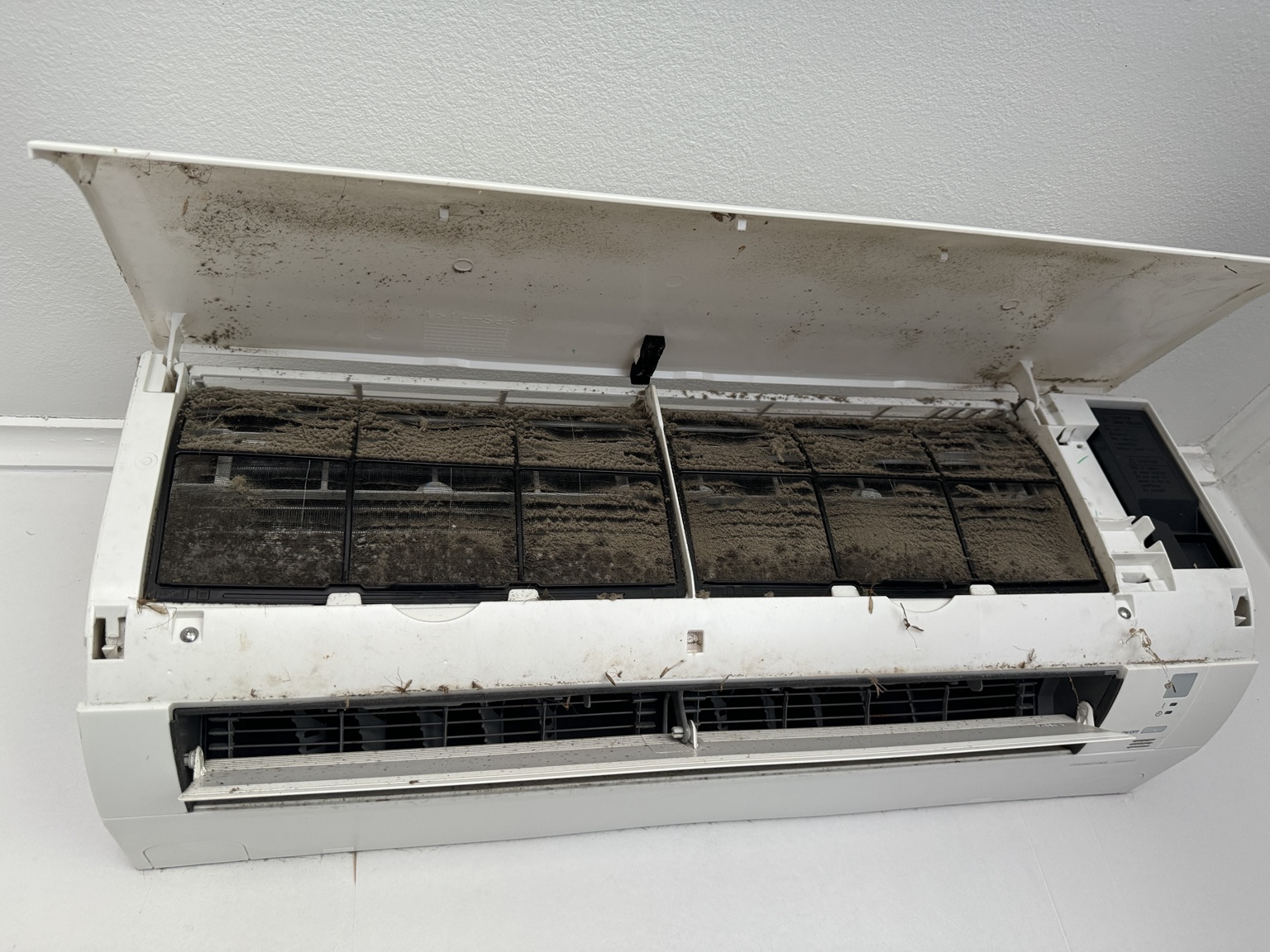 Thick dust on the filters inside an open wall mounted heat pump